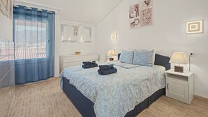 Een slaapkamer met een bed, nachtkastjes, een spiegel en kunstwerken aan de wanden.