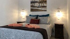 A bedroom with a bed, two nightstands, a painting, and wall sconces. - Holiday Home 'Panoramic Ocean View' with Shared Pool, Wi-Fi and Air Conditioning (Playa del Inglés)