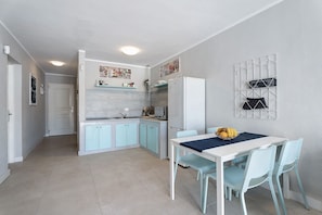 Una cocina compacta con armarios azul claro, un refrigerador blanco y un comedor con mesa y sillas.