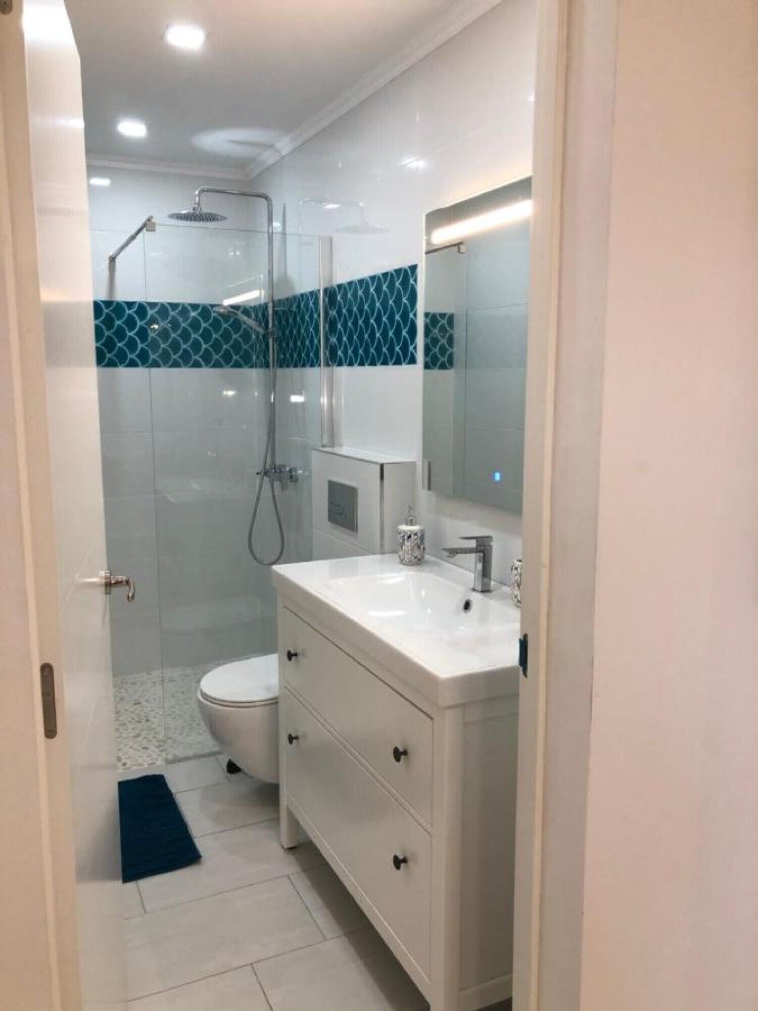 Une salle de bain équipée d’une douche, de toilettes et d’un meuble-lavabo avec un miroir.