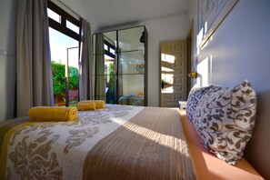 A bedroom with a bed, curtains, a window, and a door.