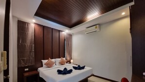 Una habitación de hotel moderna con techo de madera, una cama grande con ropa blanca, una mesita de noche y un equipo de aire acondicionado en la pared.