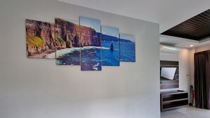 Un pasillo con una obra de arte colgada en la pared que representa una escena costera.