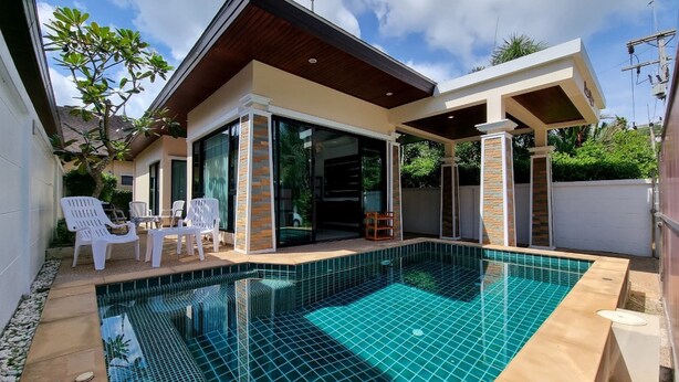 Una casa moderna con piscina, un porche cubierto y un jardín.