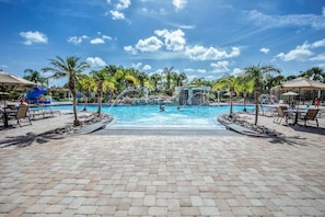Uma área de piscina com espreguiçadeiras, palmeiras e um toboágua.