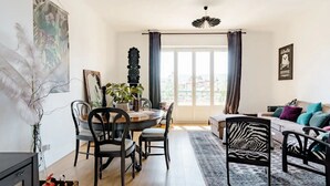 Una sala de estar moderna con comedor, que incluye un ventanal grande, una silla estampada de cebra y un sofá con cojines coloridos.