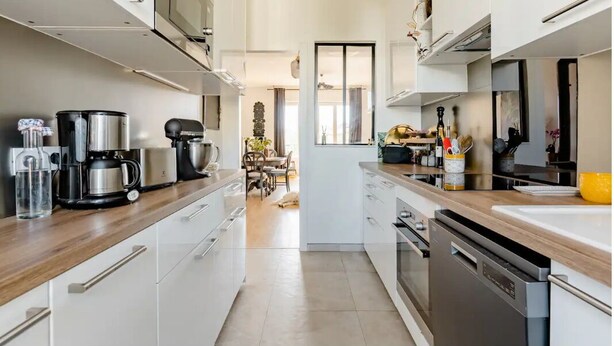 Una cocina moderna con armarios blancos, electrodomésticos de acero inoxidable y encimera de madera.
