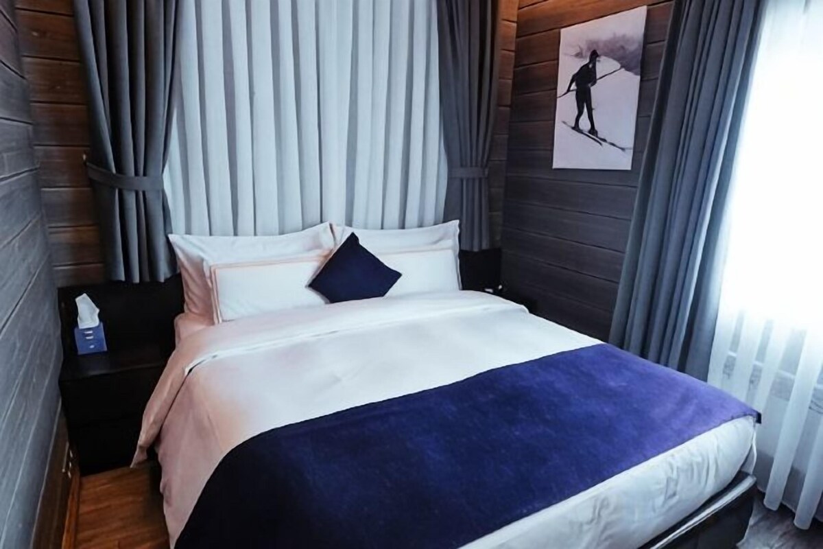 A bed with a white and blue bedspread, a dark blue pillow, and a nightstand with a lamp.
