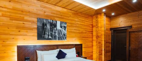 Un dormitorio con paneles de madera, una cama, mesitas de noche y una fotografía enmarcada en la pared.