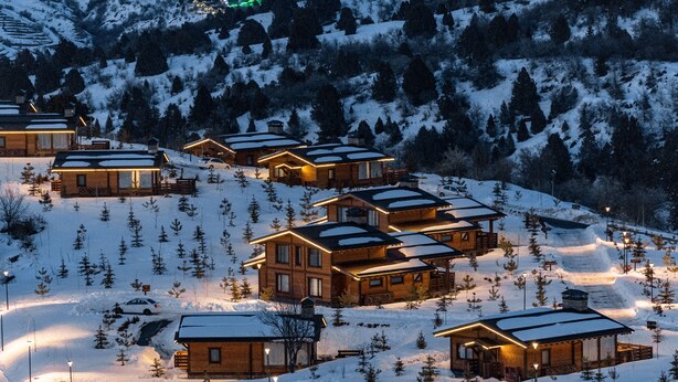 Une station de montagne enneigée, avec des chalets en bois et un télésiège.