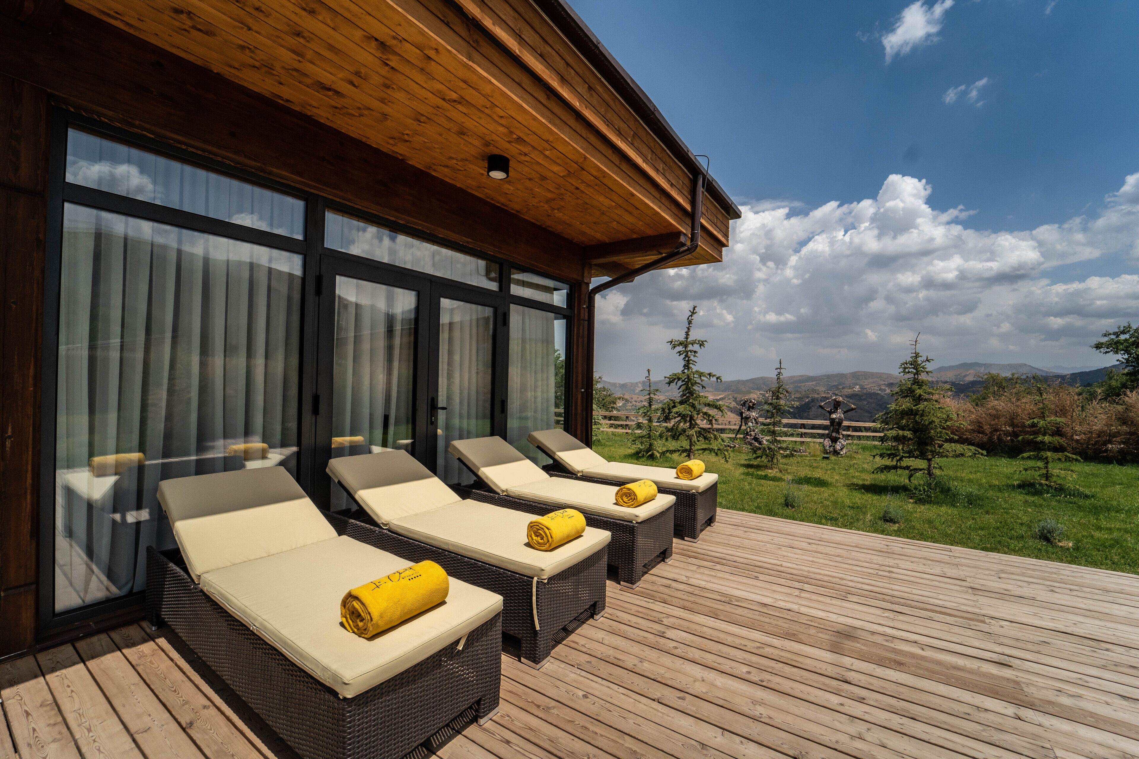Um terraço com quatro espreguiçadeiras, cada uma com uma toalha, com vista para uma paisagem deslumbrante.