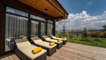 Um terraço com quatro espreguiçadeiras, cada uma com uma toalha, com vista para uma paisagem deslumbrante.