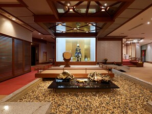 Un interior japonés tradicional con suelo de tatami, una exhibición central de artefactos culturales y un diseño de techo moderno.