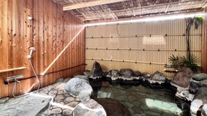 Tinaja de piedra con cubierta de madera y pared de bambú.