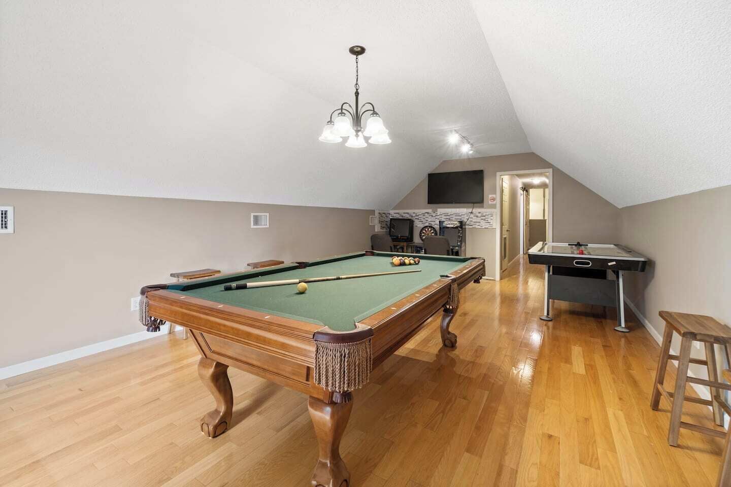 Ein Billardtisch in einem Raum mit Holzboden und schrägverdeckter Decke.
