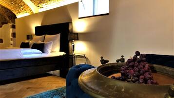 Een slaapkamer met een bed, nachtkastje, lamp en een messing schaal met druiven.