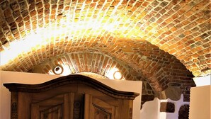 An arched brick ceiling, a wooden wardrobe, and a stone wall. - HLH Exklusives Suite Colloseum (Freiburg im Breisgau)