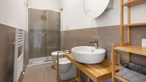 Une salle de bain moderne avec une douche à parois de verre, un lavabo blanc et des étagères en bois.