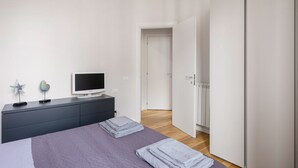 Une chambre à coucher avec un lit, un téléviseur posé sur une commode et une armoire.
