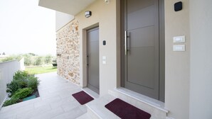 A modern building entrance with two doors, a stone wall, and a small garden area.