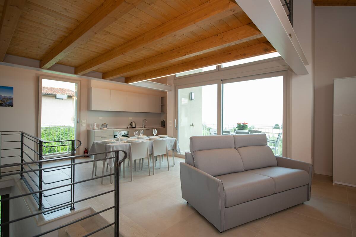 Una sala de estar moderna con sofá, comedor, cocina y un balcón con vistas.