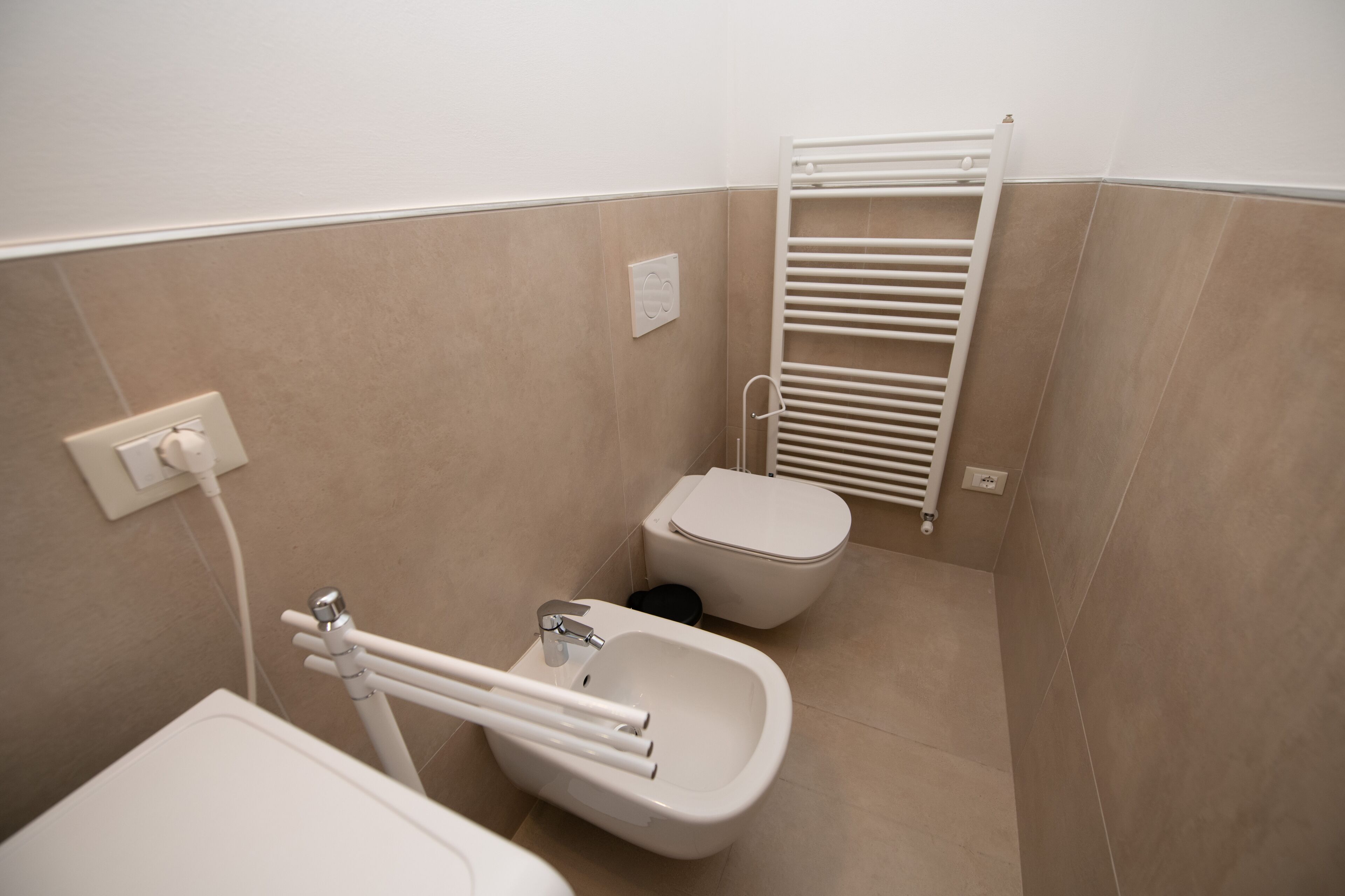A bathroom with a bidet, toilet, and a towel rack.