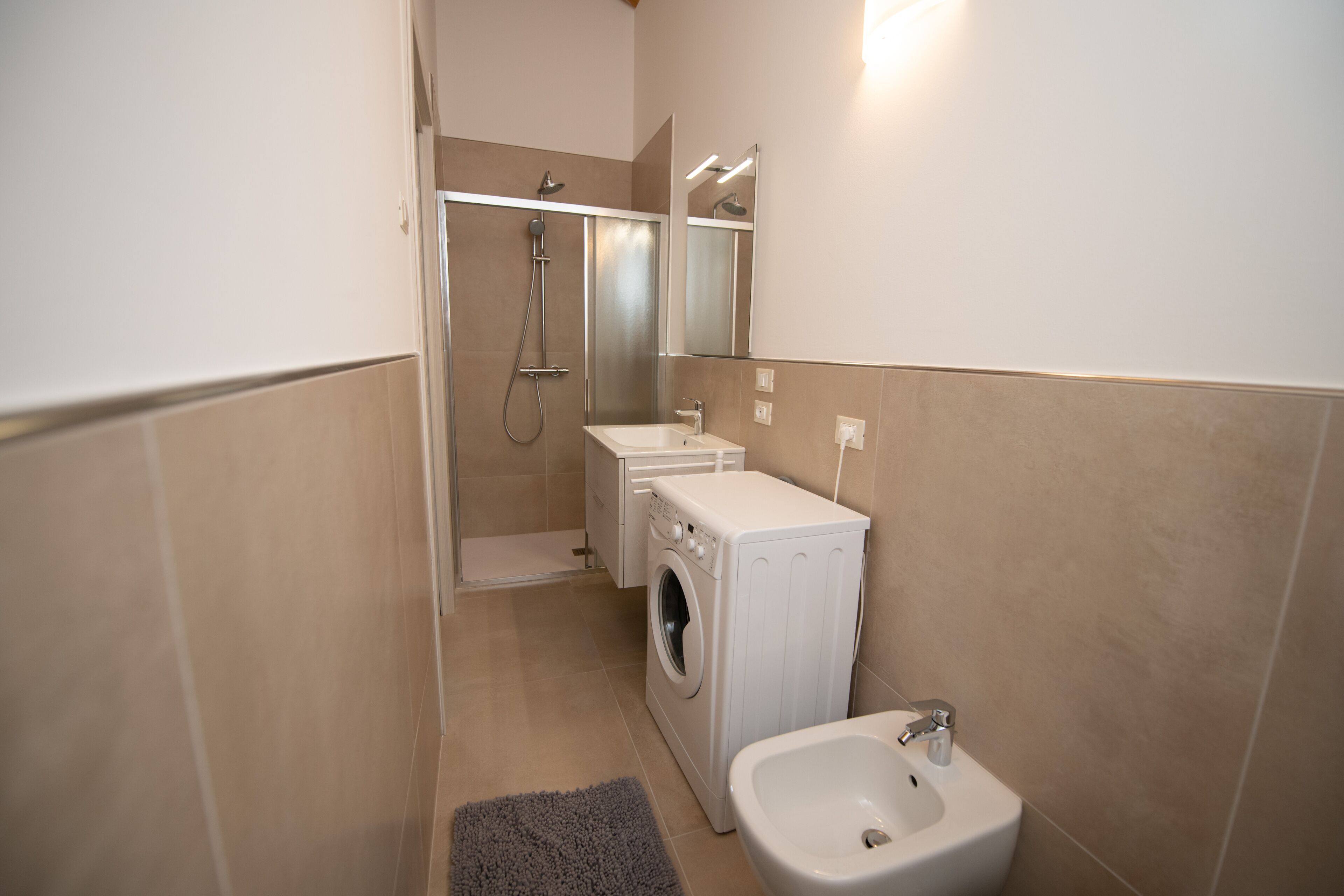 A compact bathroom with a shower, washing machine, and bidet.