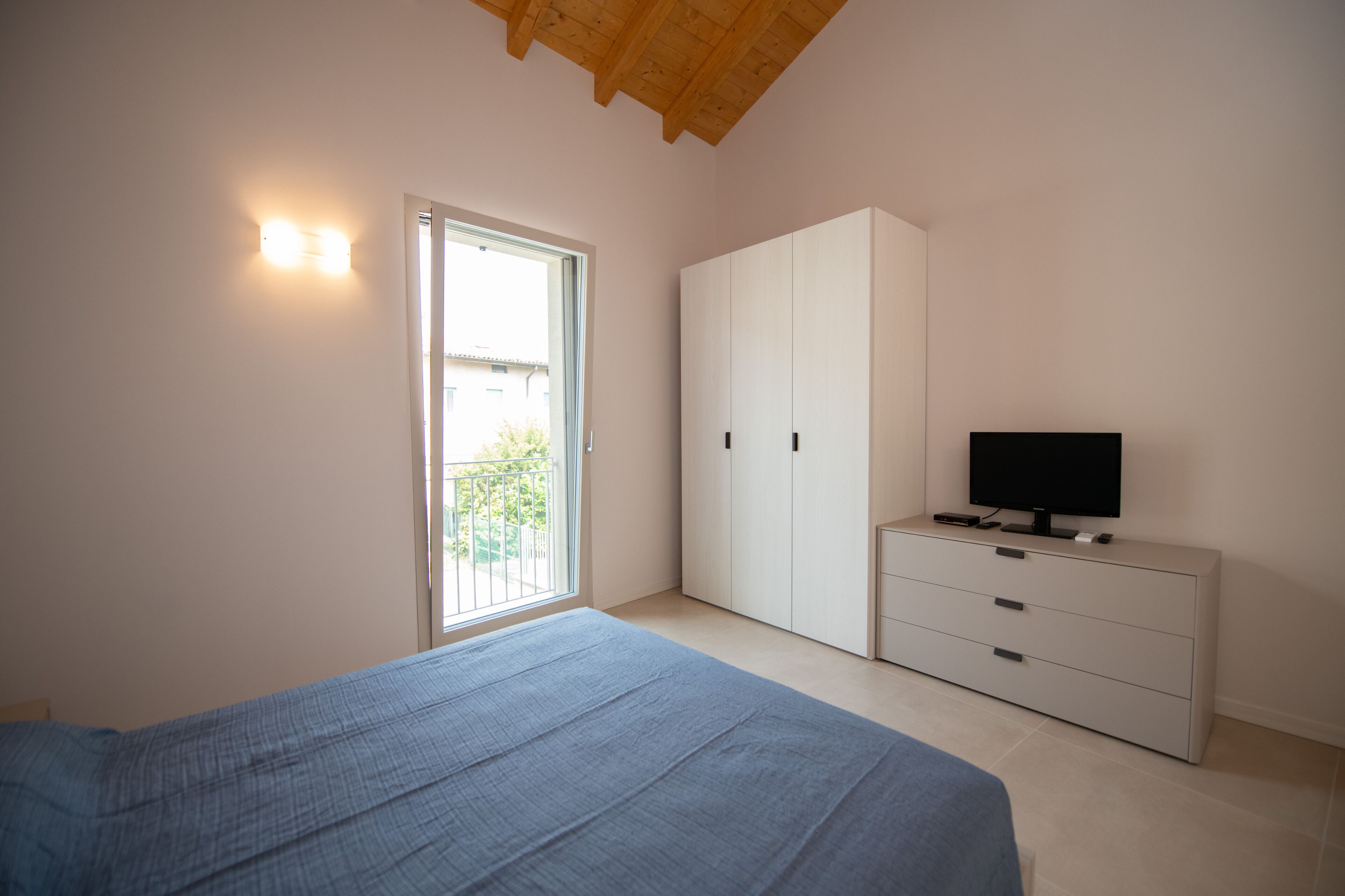 A bedroom with a bed, a wardrobe, a television, and a window.
