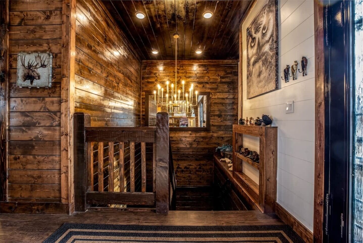 A wooden interior with a staircase, a chandelier, and wall-mounted decorations.