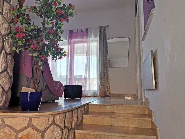 A staircase leading to a room with a stone wall, a potted plant, and a mirror.
