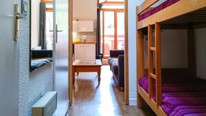 A compact room with a bunk bed, a kitchenette, and a sofa. - Studio with balcony in central Brides-les-Bains, WiFi and parking (Brides-les-Bains)