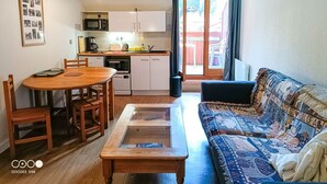 A compact living space with a dining table, sofa, and kitchenette. - Studio with balcony in central Brides-les-Bains, WiFi and parking (Brides-les-Bains)