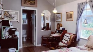 Een knus slaapkamer met een bed, een bureau, een stoel en een raam met gordijnen.
