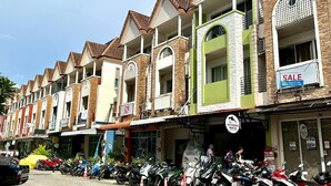 A row of multi-story buildings with a row of parked motorcycles in front. - Sea Boss Homestay (Karon)