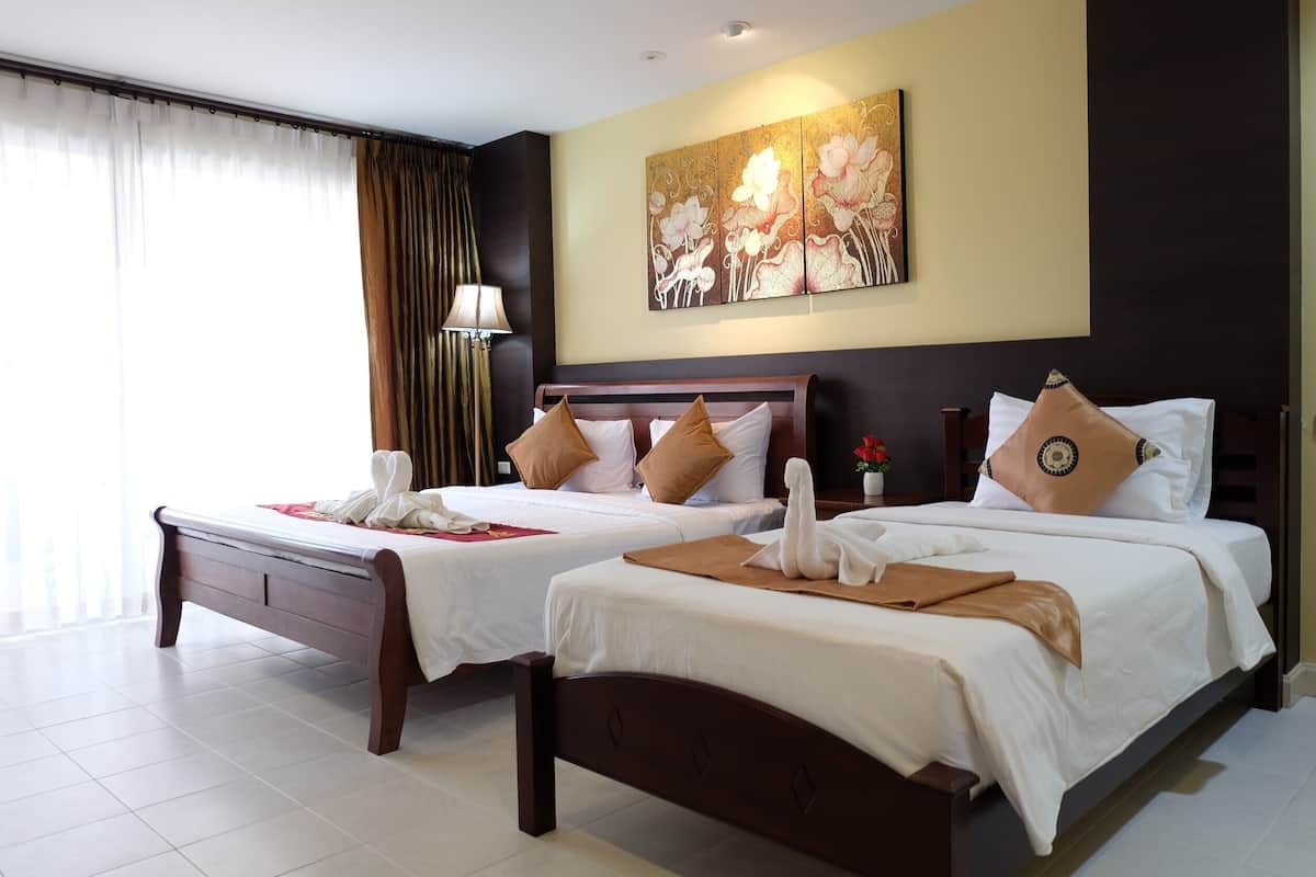 A hotel room with two beds, a large painting on the wall, and a window with curtains.