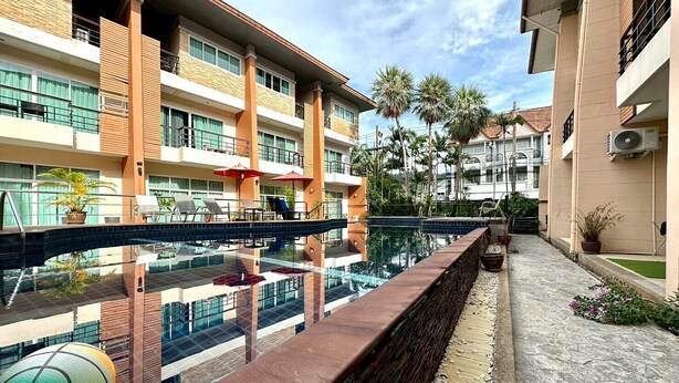 A hotel with a swimming pool, multiple balconies, and outdoor seating areas. - Sea Boss Homestay (Karon)