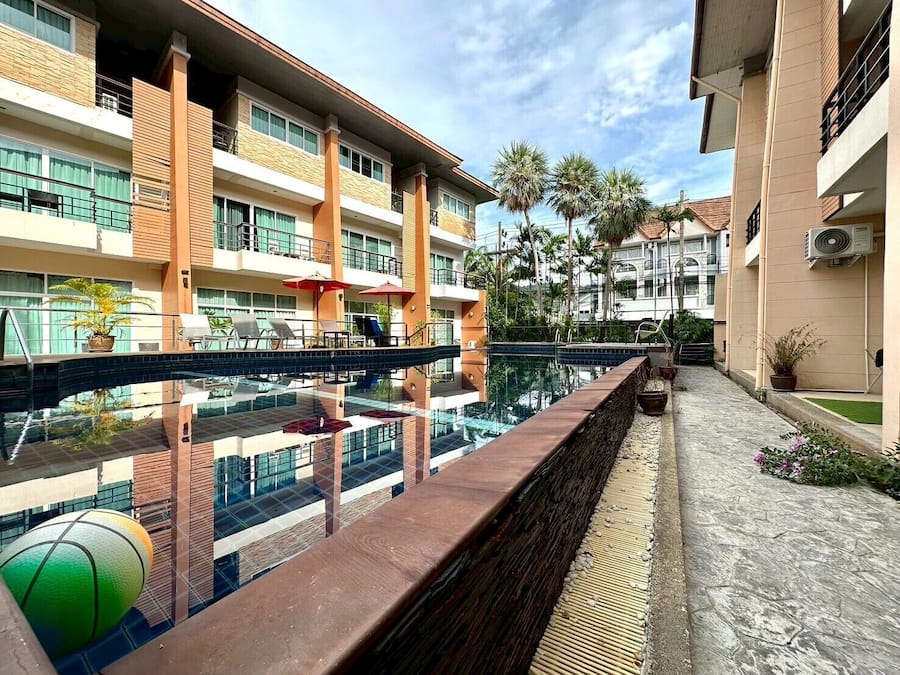 Un hotel con piscina, varios balcones y zonas de estar al aire libre.