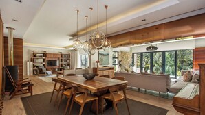 Una cocina amplia con una gran mesa de madera y sillas, un colgante de luz y vistas al exterior a través de ventanas grandes.