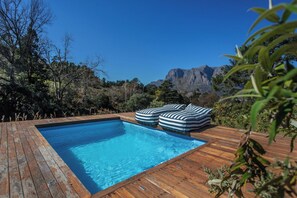 Una piscina con cubierta de madera y dos cojines a rayas.