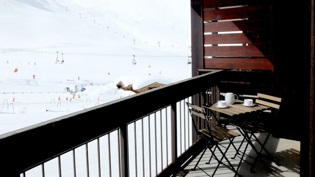 A balcony with a view of a snowy mountain and ski slopes.