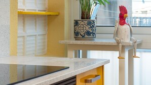 Un comptoir de cuisine avec une tablette, un pot en céramique décoratif orné de motifs floraux et une décoration rustique représentant un coq, posée sur une étagère.