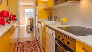 Une cuisine moderne avec des armoires jaunes, un four encastré, une plaque de cuisson et un évier.