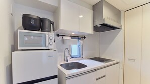 A compact kitchen with a microwave, a sink, and cabinets. - TORA HOTEL Sensoji MOON (Tokyo)