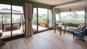 Amplia sala de estar con un gran ventanal corredero que da a un balcón, un sofá, una mesa de centro y un televisor.