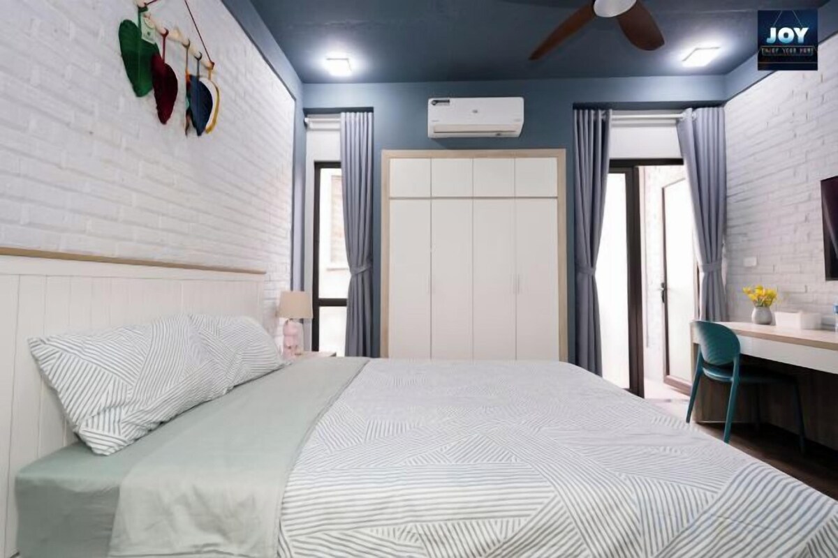 Quarto com cama, escrivaninha, cadeira, ventoinha no teto e guarda-roupa.