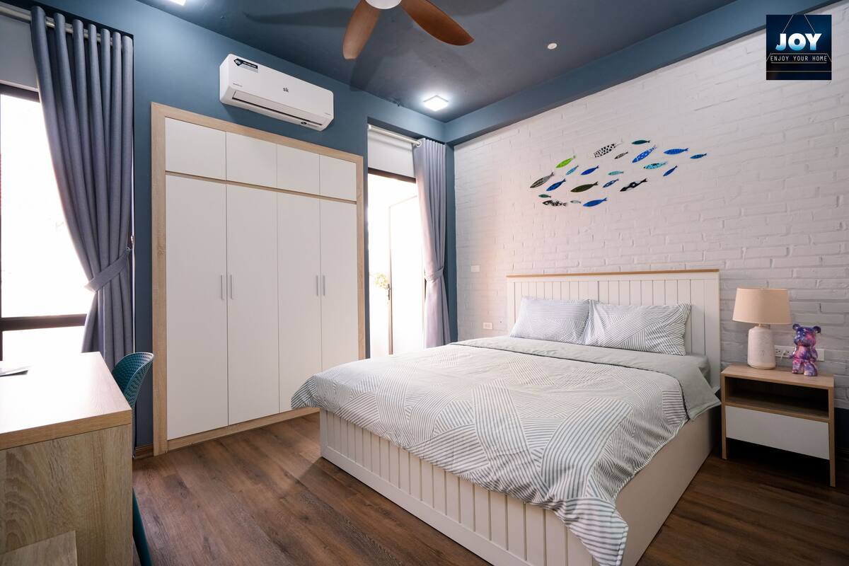 A bedroom with a bed, a desk, a wardrobe, and a wall with fish decals.