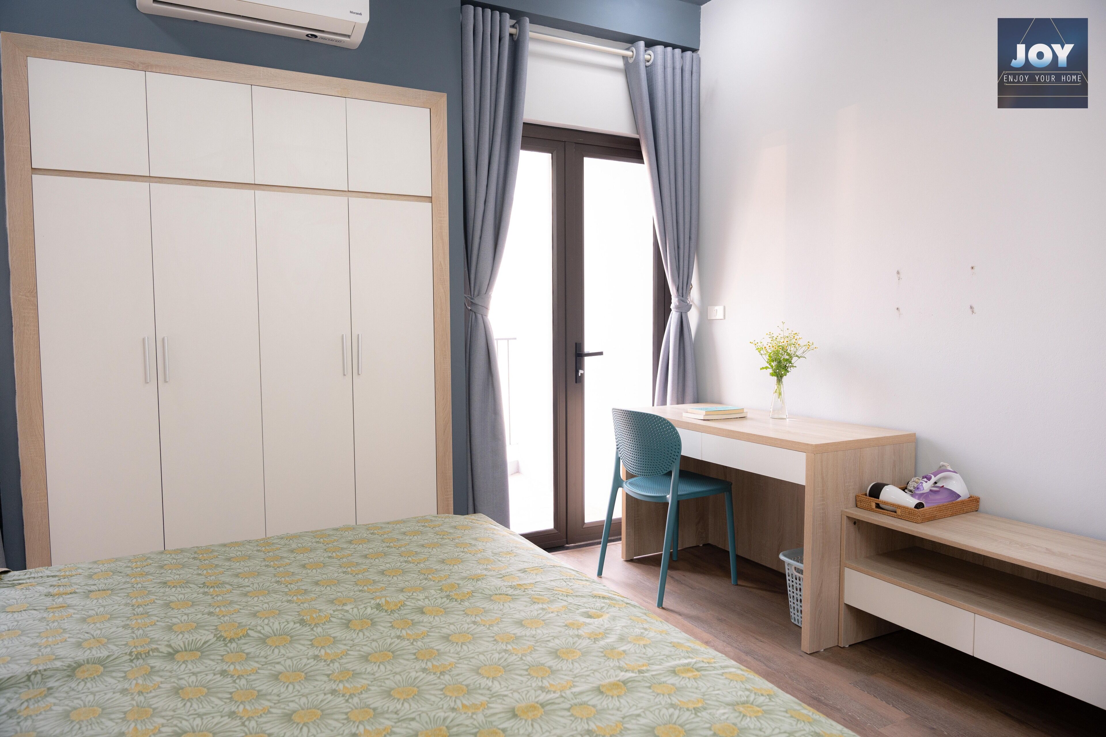 A bedroom with a bed, a desk, a chair, a wardrobe, and a window with curtains.