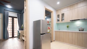 Una cocina moderna con armarios de madera, un refrigerador de acero inoxidable y un comedor con una silla y mesa.