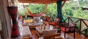 A cozy outdoor seating area with wicker furniture, a hammock, and a view of lush greenery. - 2 Bedroom Apartment in fort de france (fort de france)