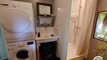 Une petite salle de bain équipée d’un lave-linge, d’un évier et d’une douche.